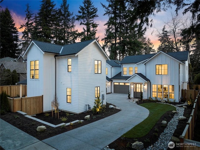 modern inspired farmhouse featuring concrete driveway, roof with shingles, an attached garage, fence, and board and batten siding