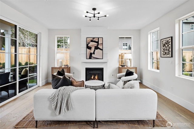 living room featuring light wood-type flooring, a large fireplace, and baseboards