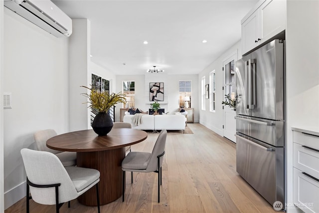 dining room with light wood-style floors, recessed lighting, an AC wall unit, and baseboards