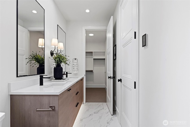 full bath with recessed lighting, marble finish floor, a sink, and double vanity