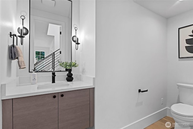 bathroom featuring vanity, wood finished floors, toilet, and baseboards