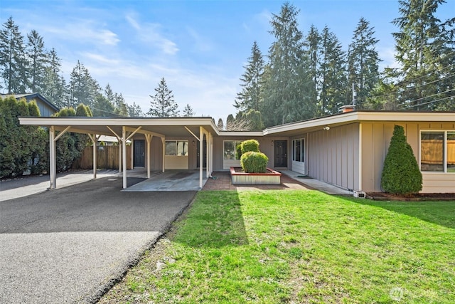 view of front of house with aphalt driveway, a front lawn, and a carport