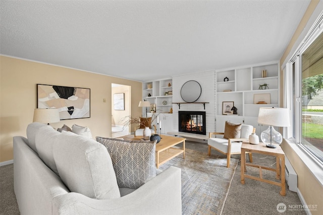 carpeted living area featuring a textured ceiling, built in shelves, a brick fireplace, and baseboards