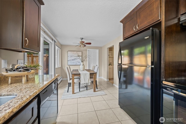 kitchen featuring a textured ceiling, light stone counters, light tile patterned flooring, dark brown cabinetry, and black appliances