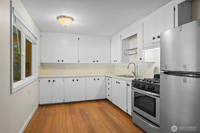 kitchen featuring under cabinet range hood, stainless steel appliances, light countertops, and light wood finished floors