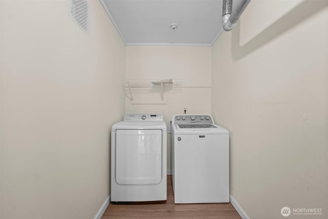 laundry room with laundry area, visible vents, baseboards, wood finished floors, and washing machine and dryer