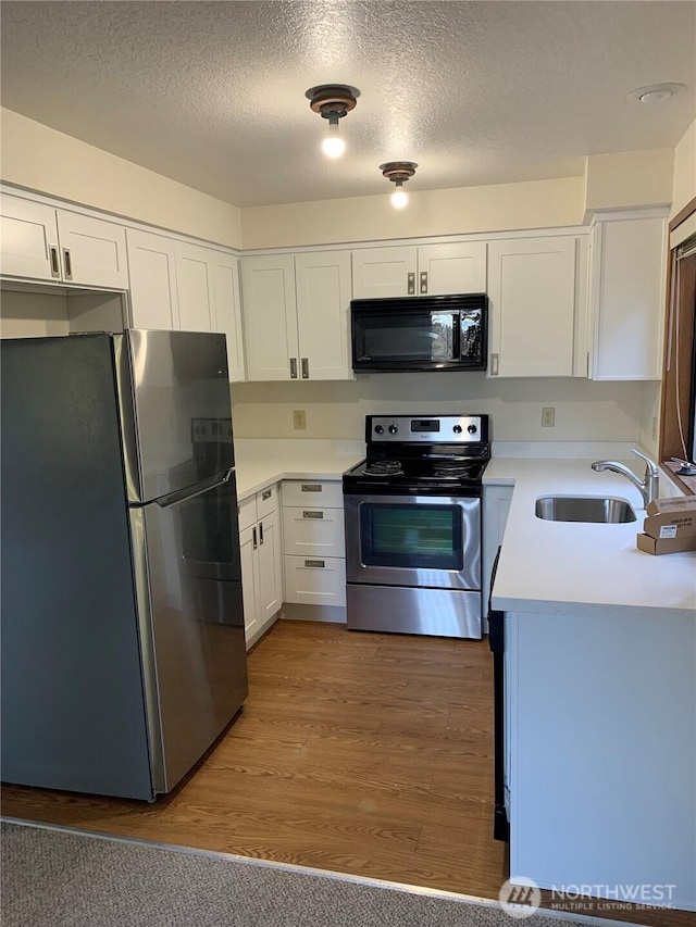 304 10th St, Kirkland, WA 98033 - kitchen with stainless steel appliances, light countertops, white cabinets, a sink, and a textured ceiling