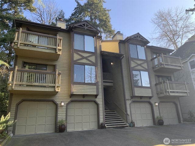 304 10th St, Kirkland, WA 98033 - view of property featuring driveway, a chimney, a garage, and a balcony