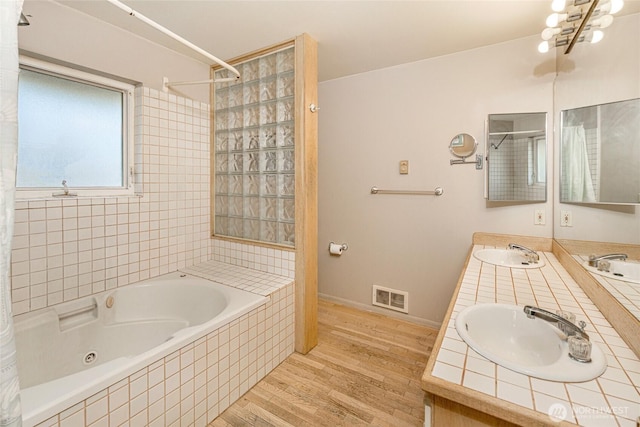 bathroom featuring visible vents, wood finished floors, baseboards, and a sink