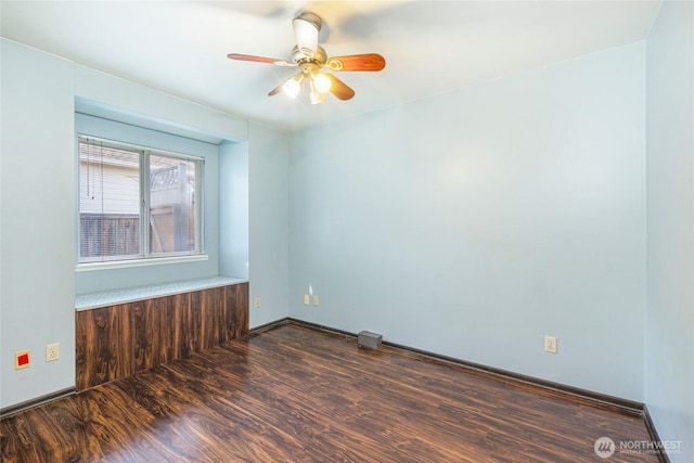 empty room featuring dark wood finished floors, a ceiling fan, and baseboards