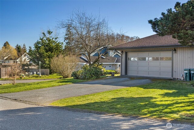 view of front facade with a front yard, a garage, driveway, and a shingled roof