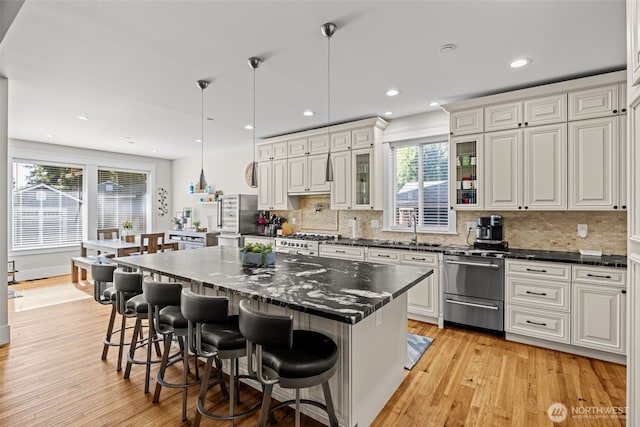 kitchen with plenty of natural light, light wood-type flooring, a sink, and decorative backsplash