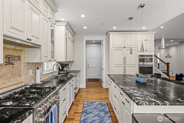 kitchen with light wood finished floors, tasteful backsplash, recessed lighting, appliances with stainless steel finishes, and white cabinetry