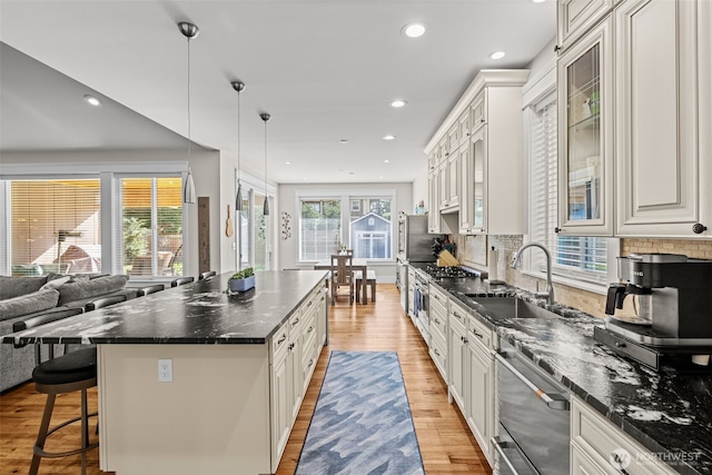 kitchen featuring light wood-style floors, a kitchen bar, a sink, and a center island