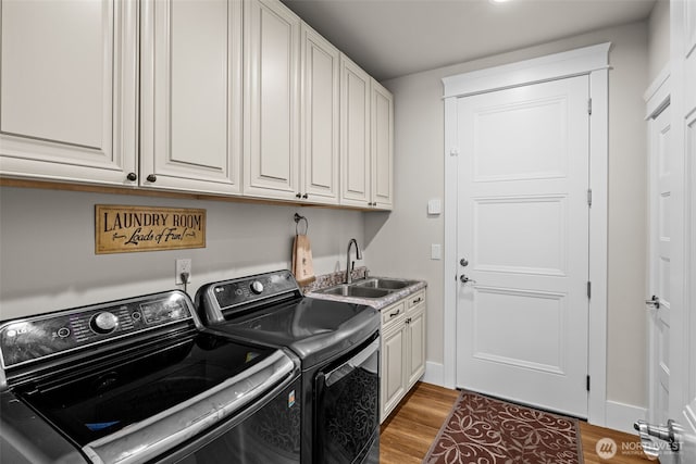 washroom featuring cabinet space, baseboards, independent washer and dryer, light wood-type flooring, and a sink