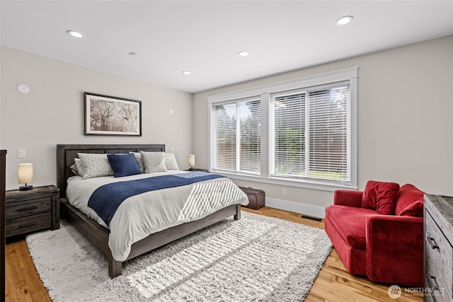 bedroom with baseboards, light wood finished floors, visible vents, and recessed lighting