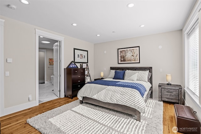 bedroom with baseboards, ensuite bathroom, wood finished floors, and recessed lighting