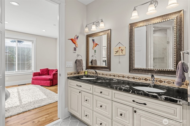 bathroom with double vanity, wood finished floors, a sink, and a shower with shower door