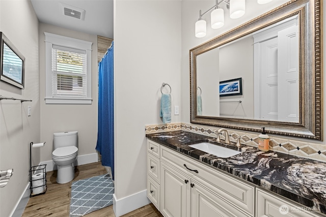 full bathroom featuring toilet, wood finished floors, vanity, visible vents, and baseboards