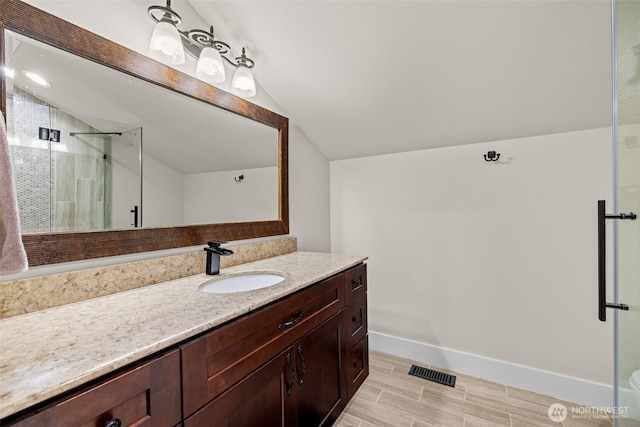 bathroom featuring visible vents, a stall shower, vaulted ceiling, vanity, and baseboards