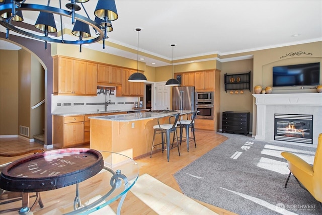 kitchen with arched walkways, a center island, stainless steel appliances, visible vents, and a kitchen bar