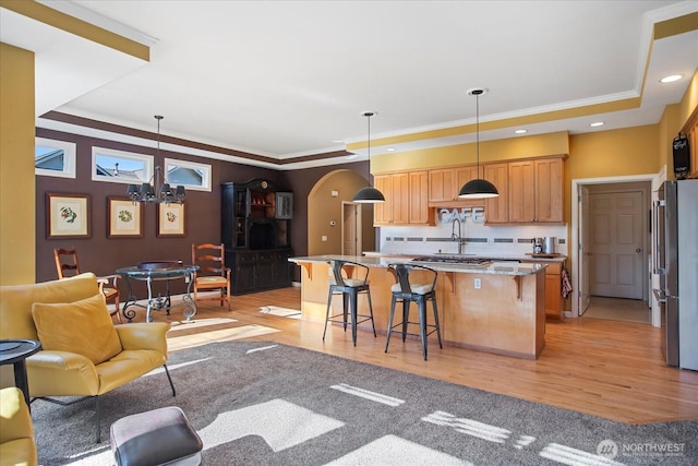 kitchen featuring arched walkways, a raised ceiling, freestanding refrigerator, open floor plan, and a kitchen bar