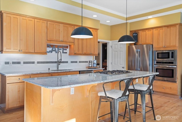 kitchen with a center island, stainless steel appliances, a sink, light wood-type flooring, and a kitchen breakfast bar