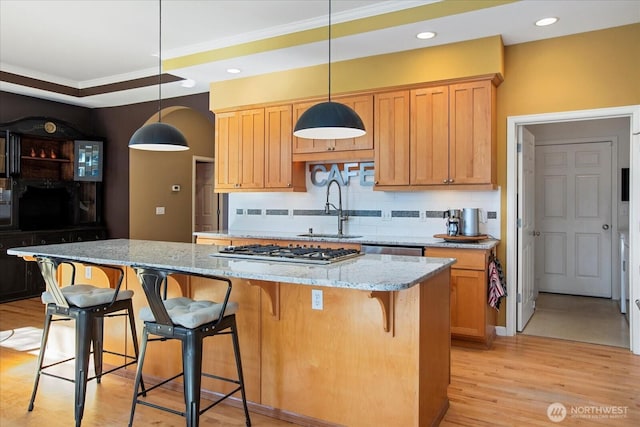 kitchen featuring light stone counters, light wood finished floors, tasteful backsplash, appliances with stainless steel finishes, and a sink