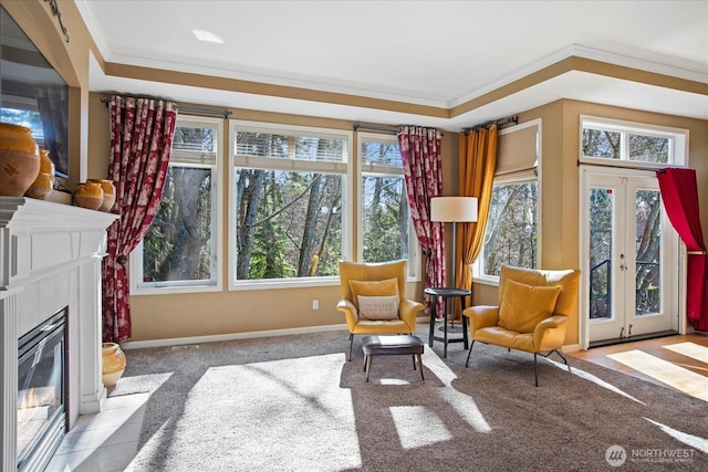 sitting room featuring baseboards, a fireplace with flush hearth, carpet, crown molding, and french doors