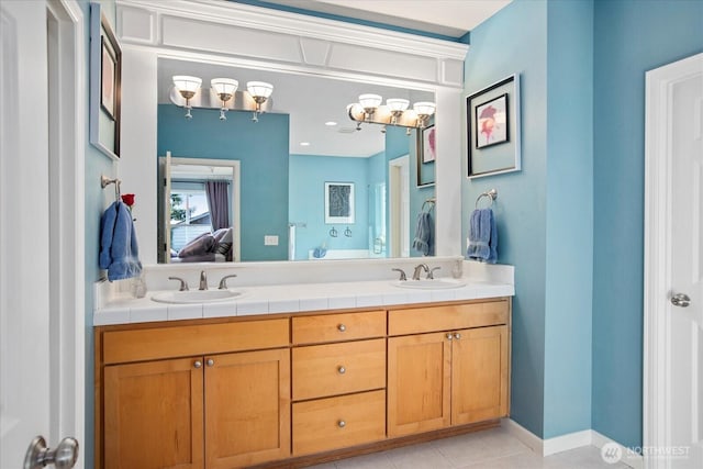 ensuite bathroom with double vanity, tile patterned flooring, connected bathroom, and a sink