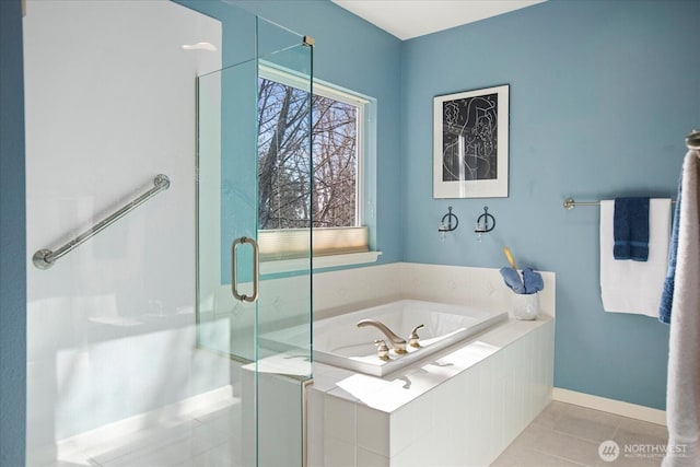 bathroom with a stall shower, tile patterned flooring, baseboards, and a garden tub