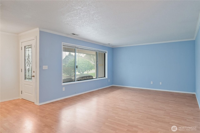 spare room featuring light wood finished floors, a textured ceiling, visible vents, and crown molding