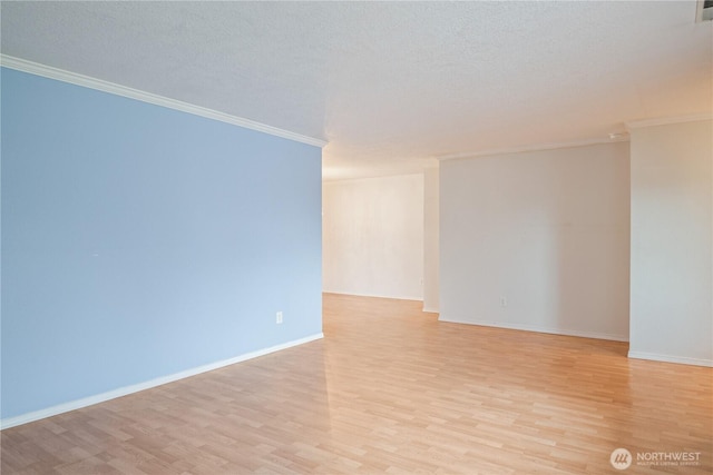 spare room with ornamental molding, baseboards, light wood-style flooring, and a textured ceiling