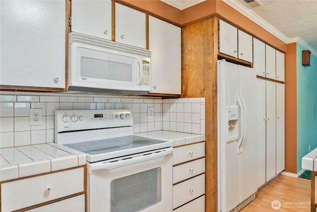 kitchen featuring ornamental molding, white appliances, light wood-style flooring, and tile counters