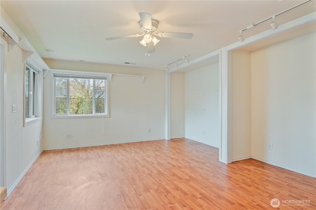 empty room featuring visible vents, ceiling fan, light wood-style flooring, and track lighting