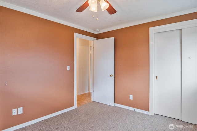 unfurnished bedroom with baseboards, ceiling fan, a textured ceiling, carpet flooring, and a closet