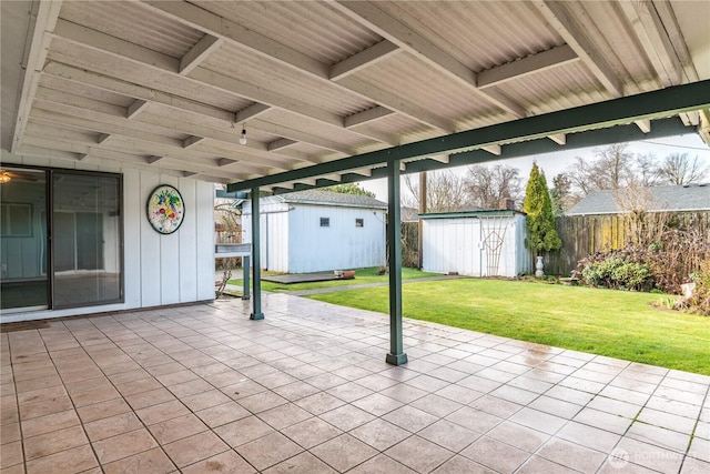 view of patio / terrace with fence, a storage unit, and an outbuilding