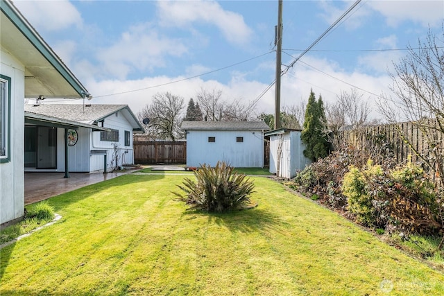 view of yard with an outbuilding, a patio area, a fenced backyard, and a shed