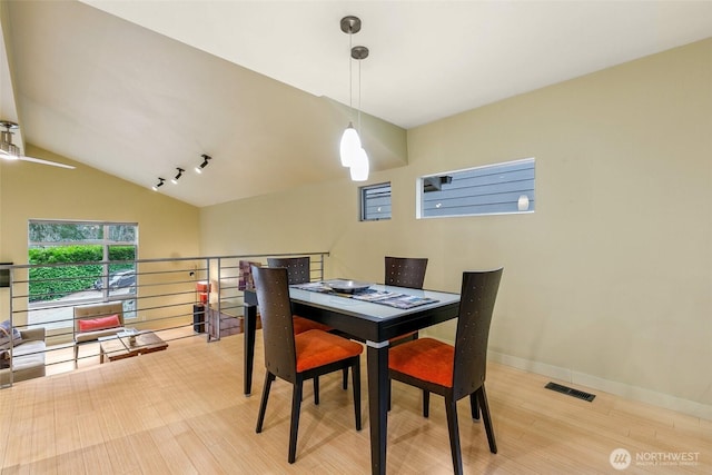 dining area featuring lofted ceiling, wood finished floors, baseboards, and visible vents