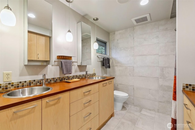 bathroom with double vanity, toilet, visible vents, and a sink