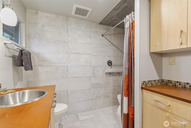 full bathroom with visible vents, toilet, backsplash, tiled shower, and vanity