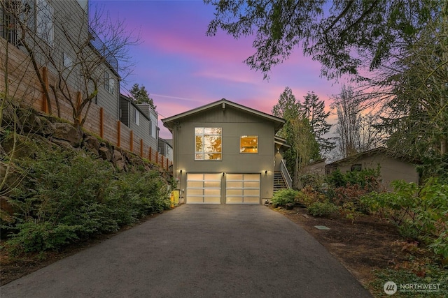 view of front of house with aphalt driveway, a garage, and stairs