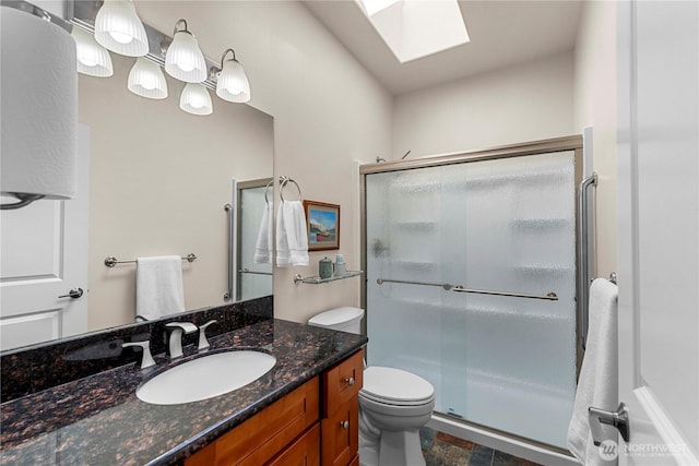 full bath featuring a stall shower, a skylight, toilet, stone finish floor, and vanity