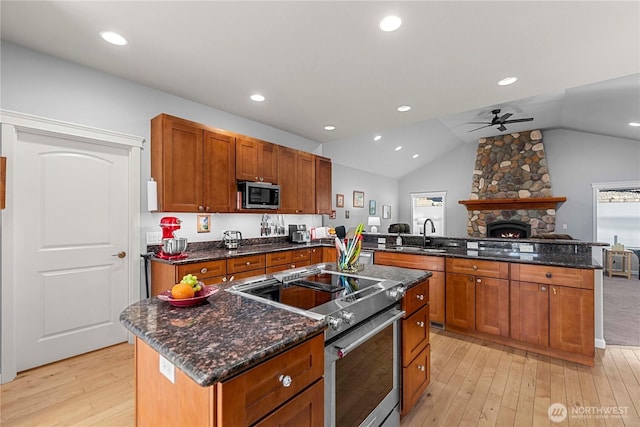 kitchen with a kitchen island, appliances with stainless steel finishes, a peninsula, light wood-style floors, and a sink