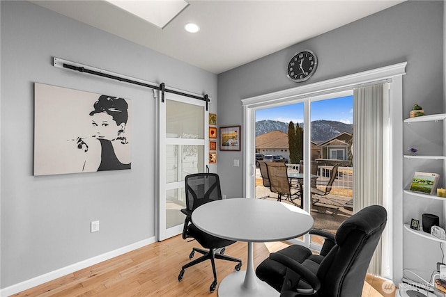 office featuring a skylight, a barn door, baseboards, light wood-style flooring, and recessed lighting