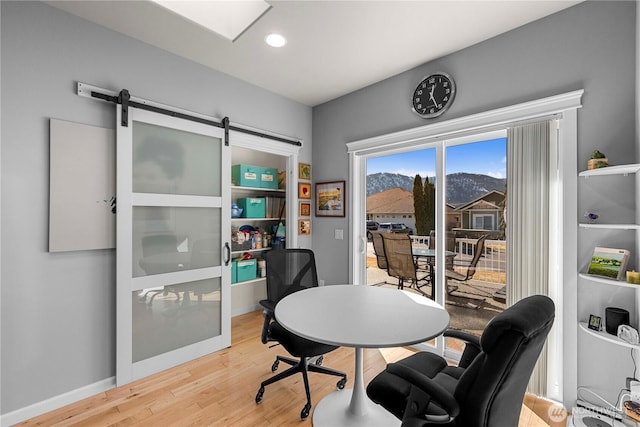 home office featuring a barn door, baseboards, wood finished floors, and recessed lighting