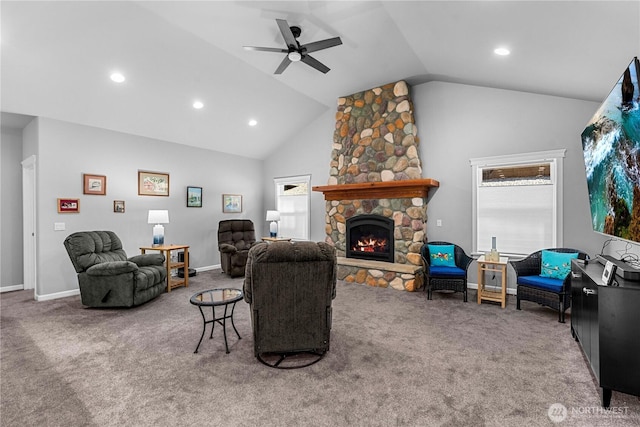 carpeted living room with ceiling fan, high vaulted ceiling, a stone fireplace, and a healthy amount of sunlight