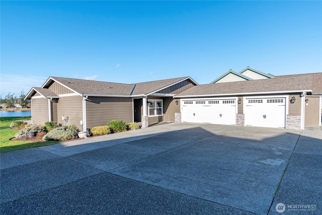 view of front of home featuring a shingled roof, stone siding, driveway, and an attached garage