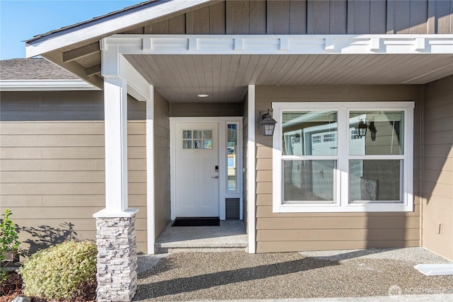 view of exterior entry with a shingled roof and board and batten siding