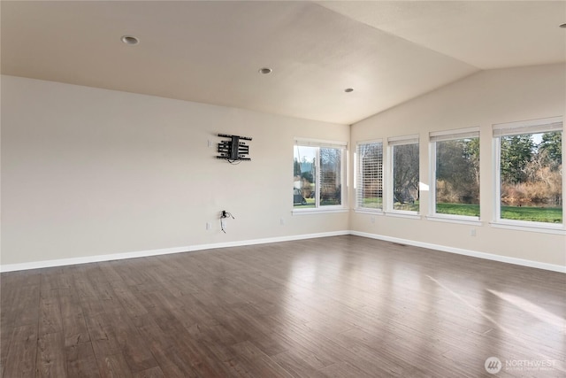 empty room featuring dark wood-style floors, vaulted ceiling, visible vents, and baseboards